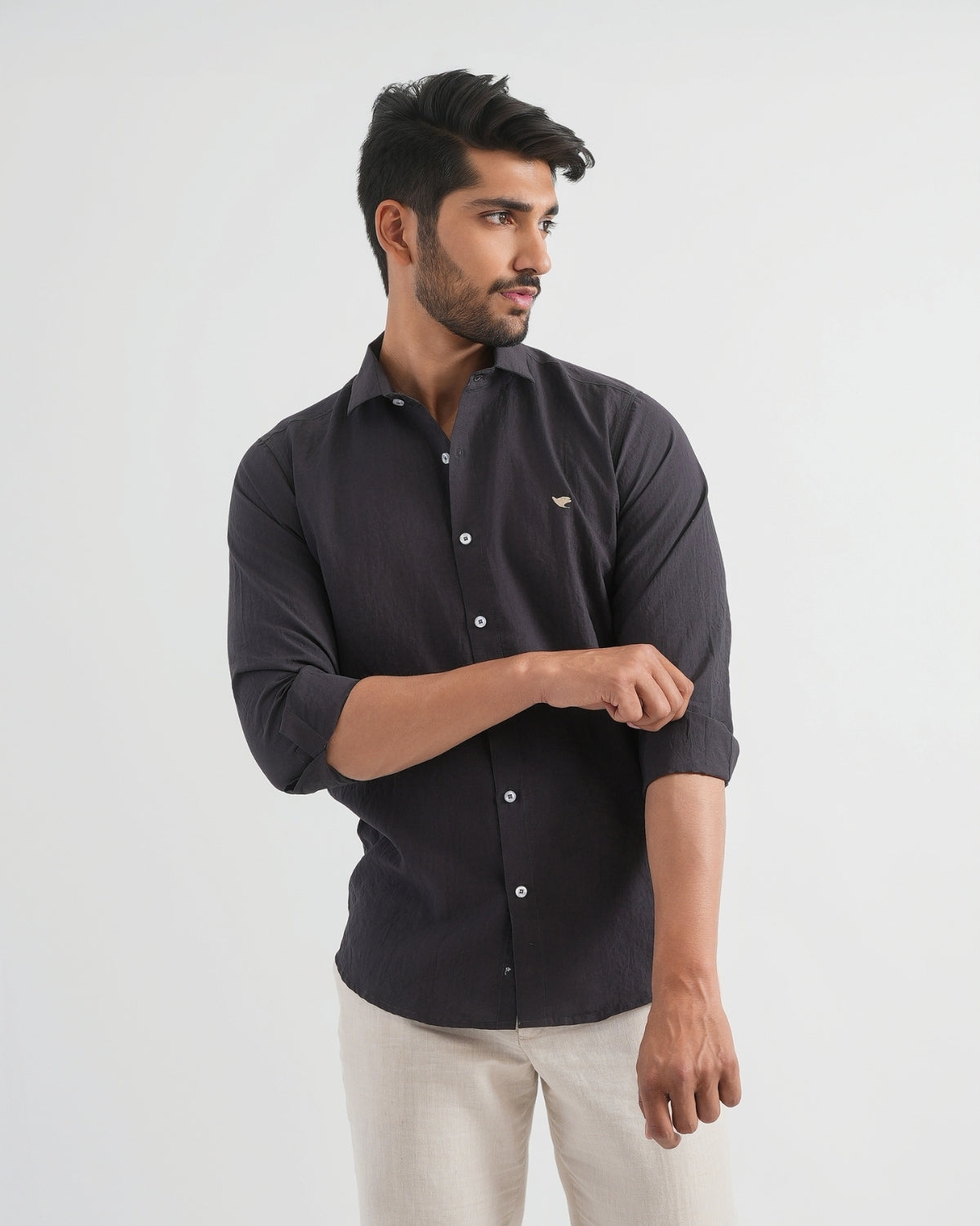 Man wearing a black shirt with a small logo on a white background