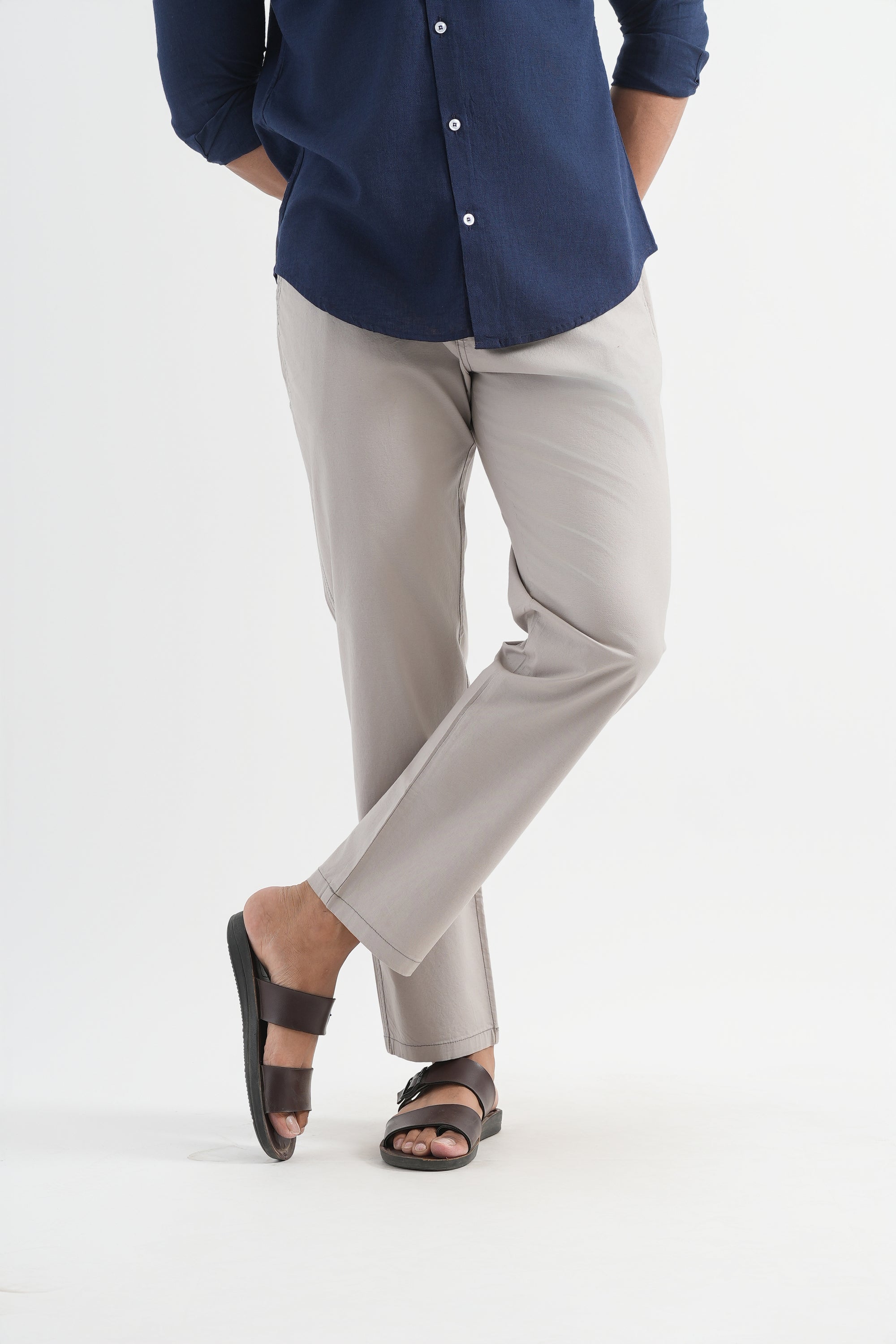 Person wearing a navy shirt and light gray pants on a white background