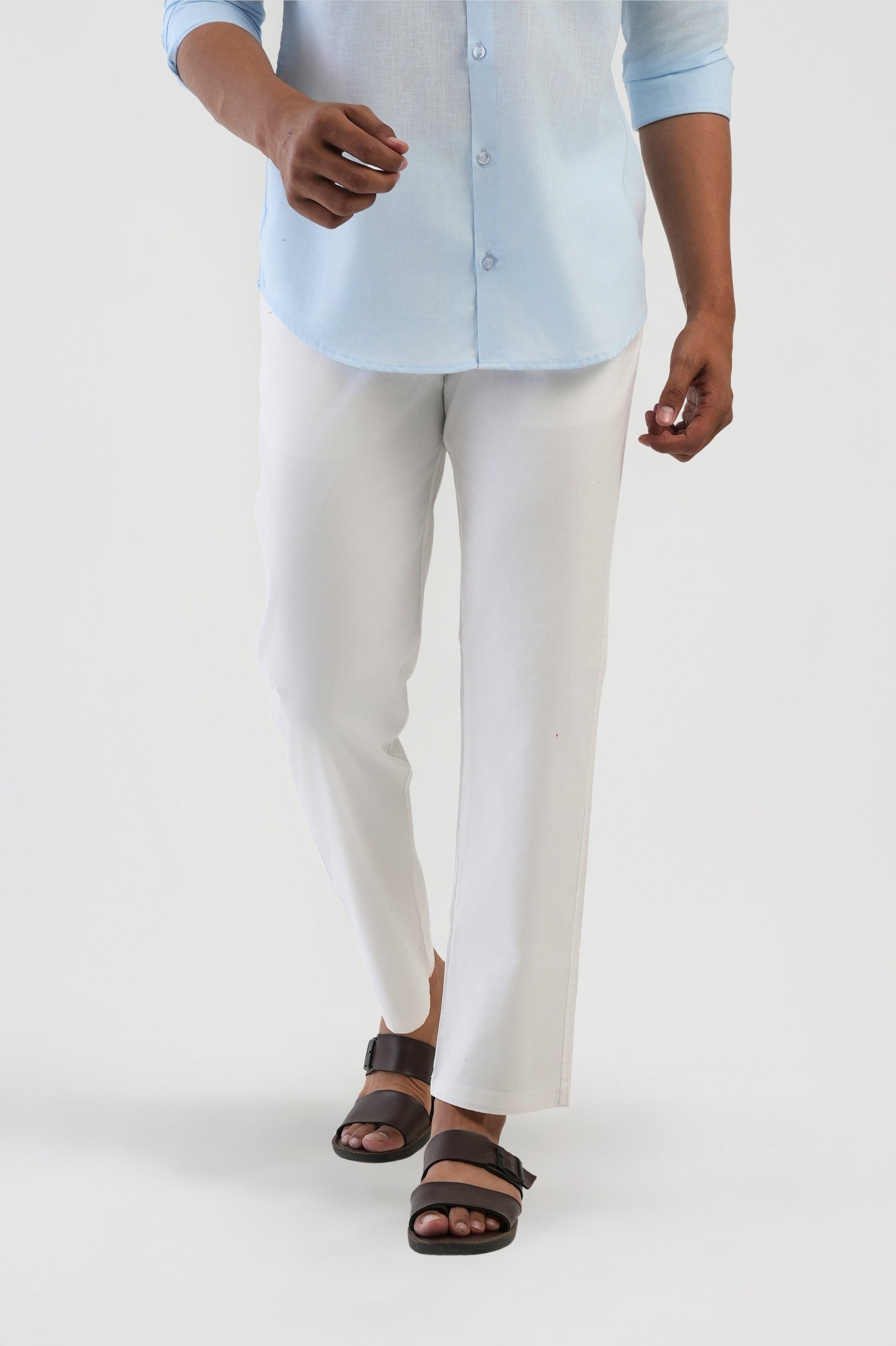 Person wearing a light blue shirt, white pants, and brown sandals on a white background