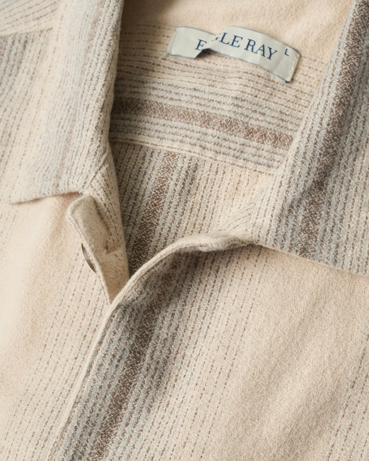 Close-up of a beige textured shirt with a brand label.