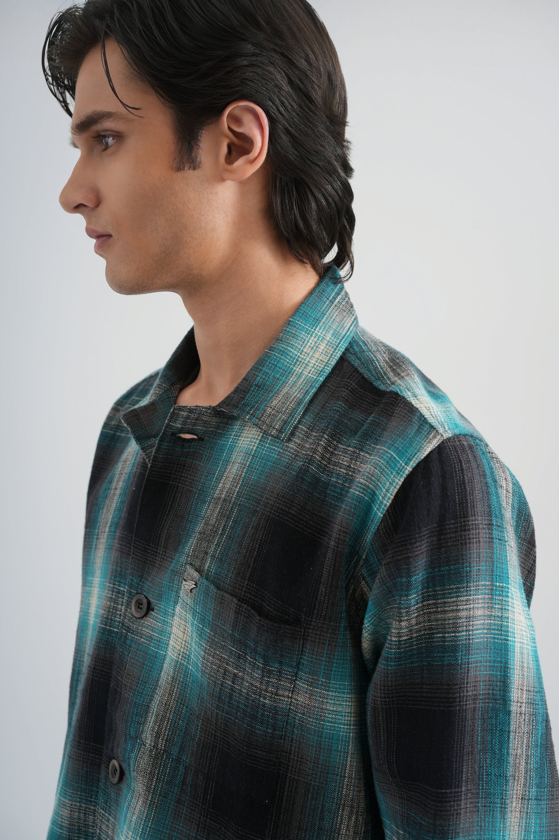 Person wearing a plaid shirt and white pants on a white background