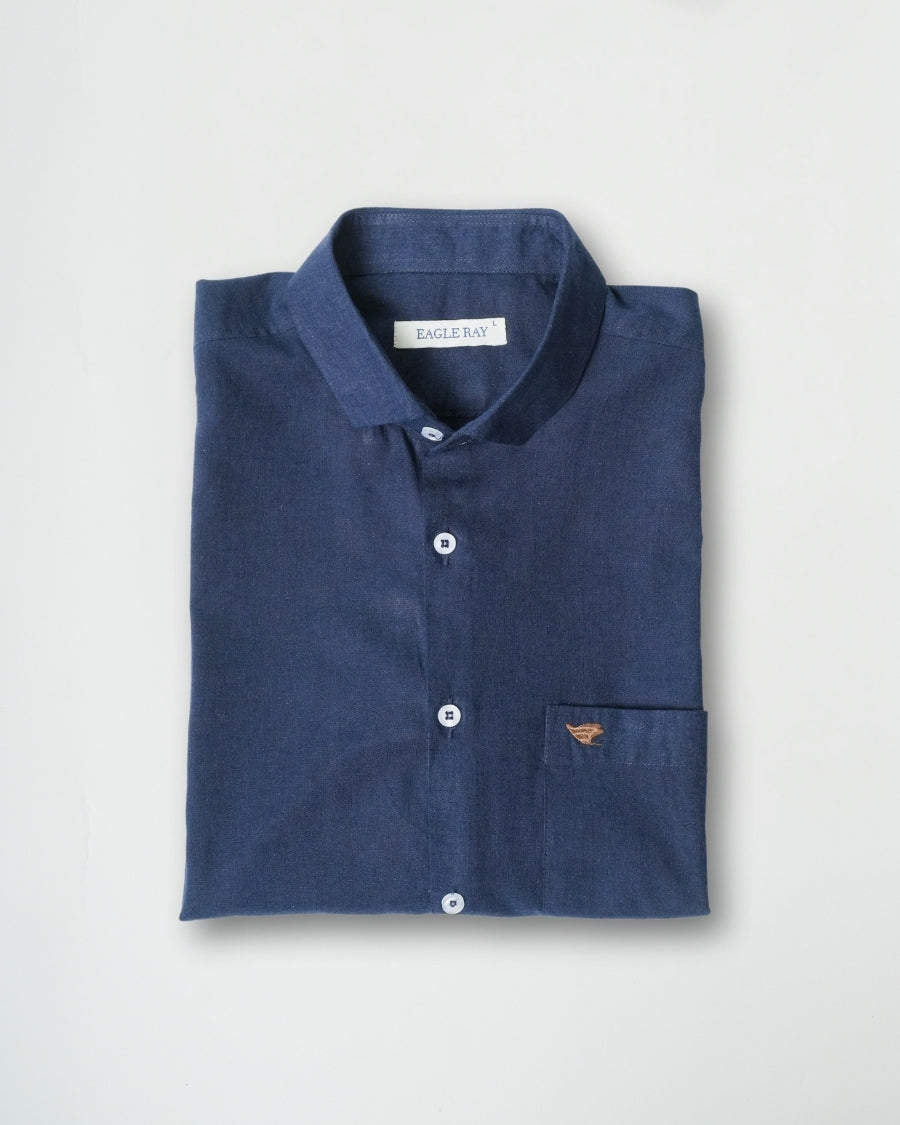 Folded navy blue shirt with a brand label on a light gray background