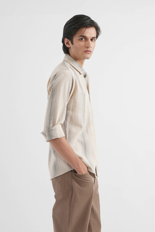 Man wearing a beige shirt and brown pants on a white background
