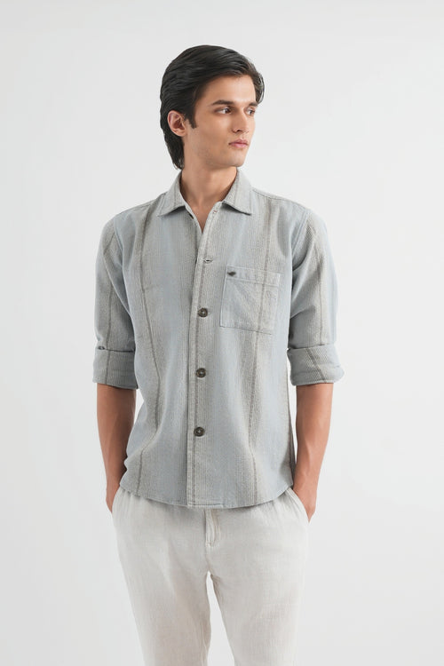 Man wearing a light gray button-up shirt and light gray pants on a white background