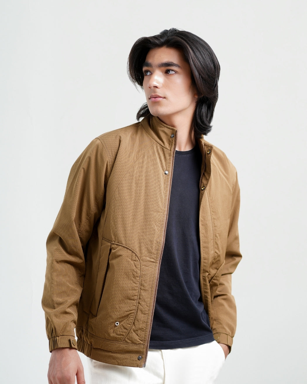 Man wearing a brown jacket over a black shirt on a white background