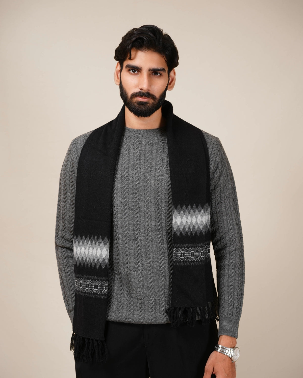 Man wearing a black and gray patterned scarf with a neutral background