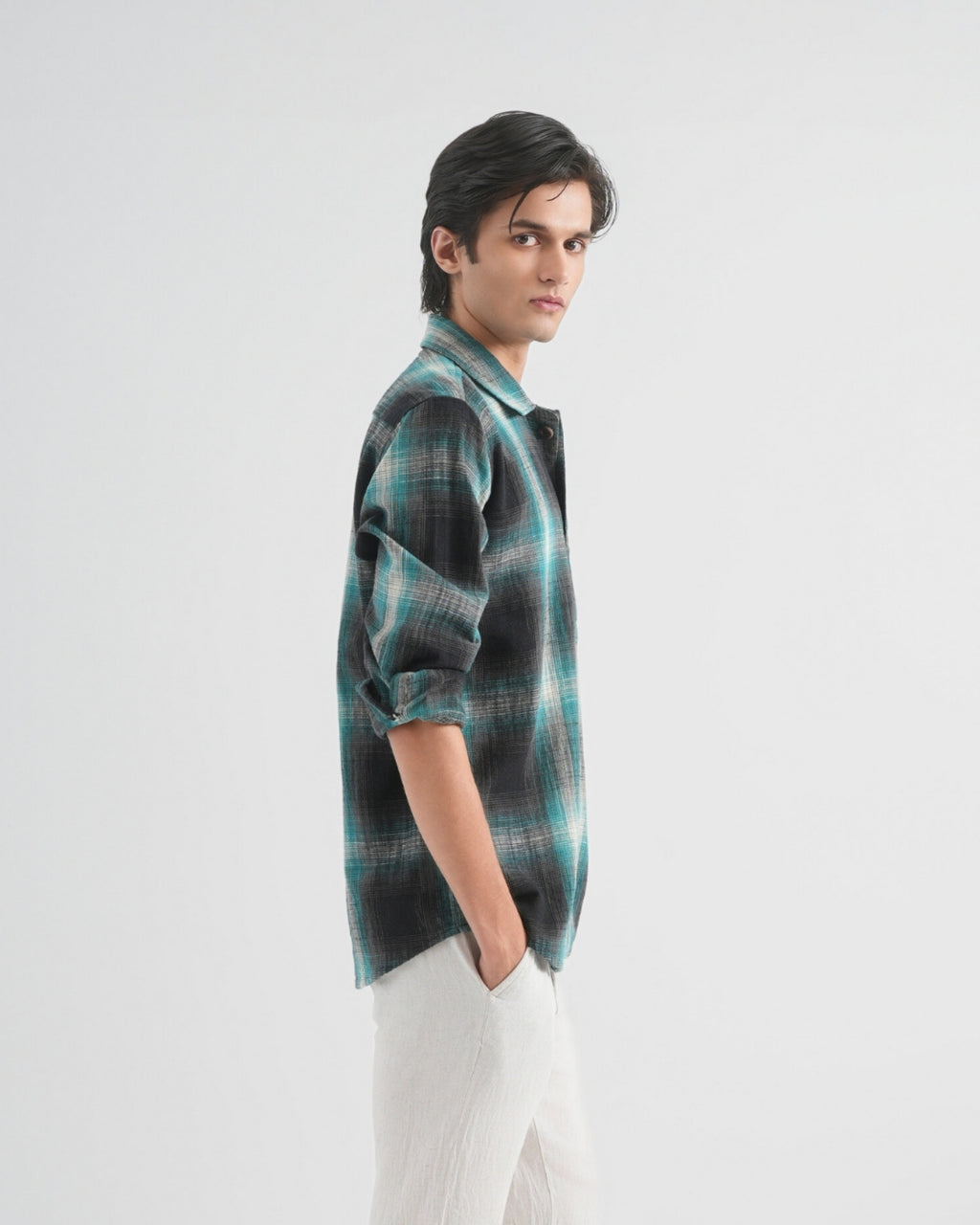 Person wearing a plaid shirt and white pants on a white background