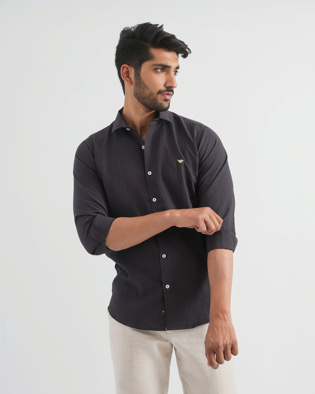 Man wearing a black shirt with a small logo on a white background