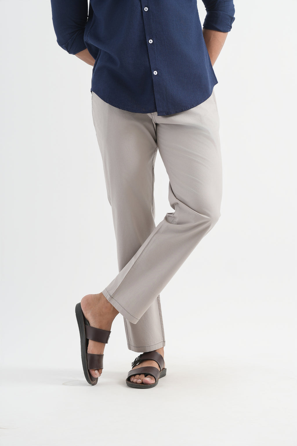 Person wearing a navy shirt and light gray pants on a white background