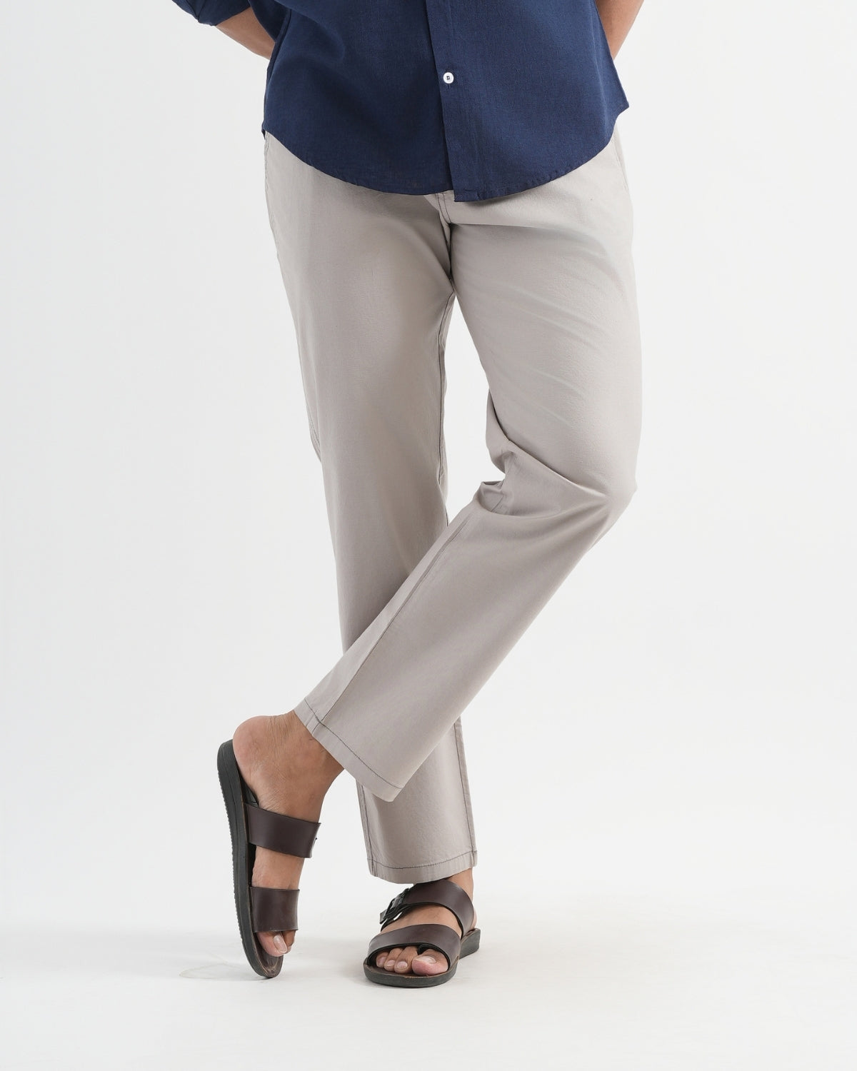 Person wearing a navy shirt, beige pants, and sandals on a white background