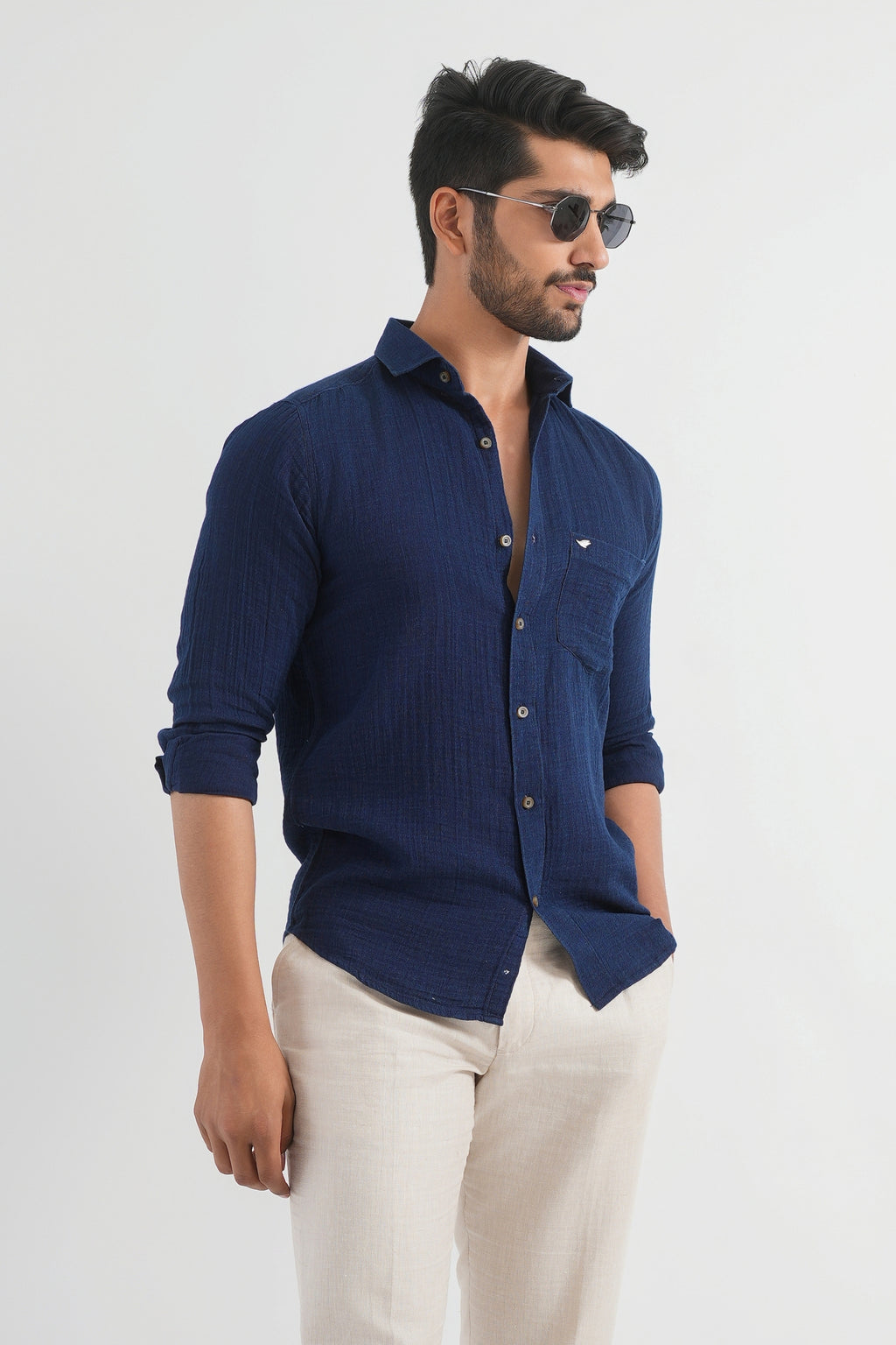 Man wearing a navy blue shirt and beige pants on a white background
