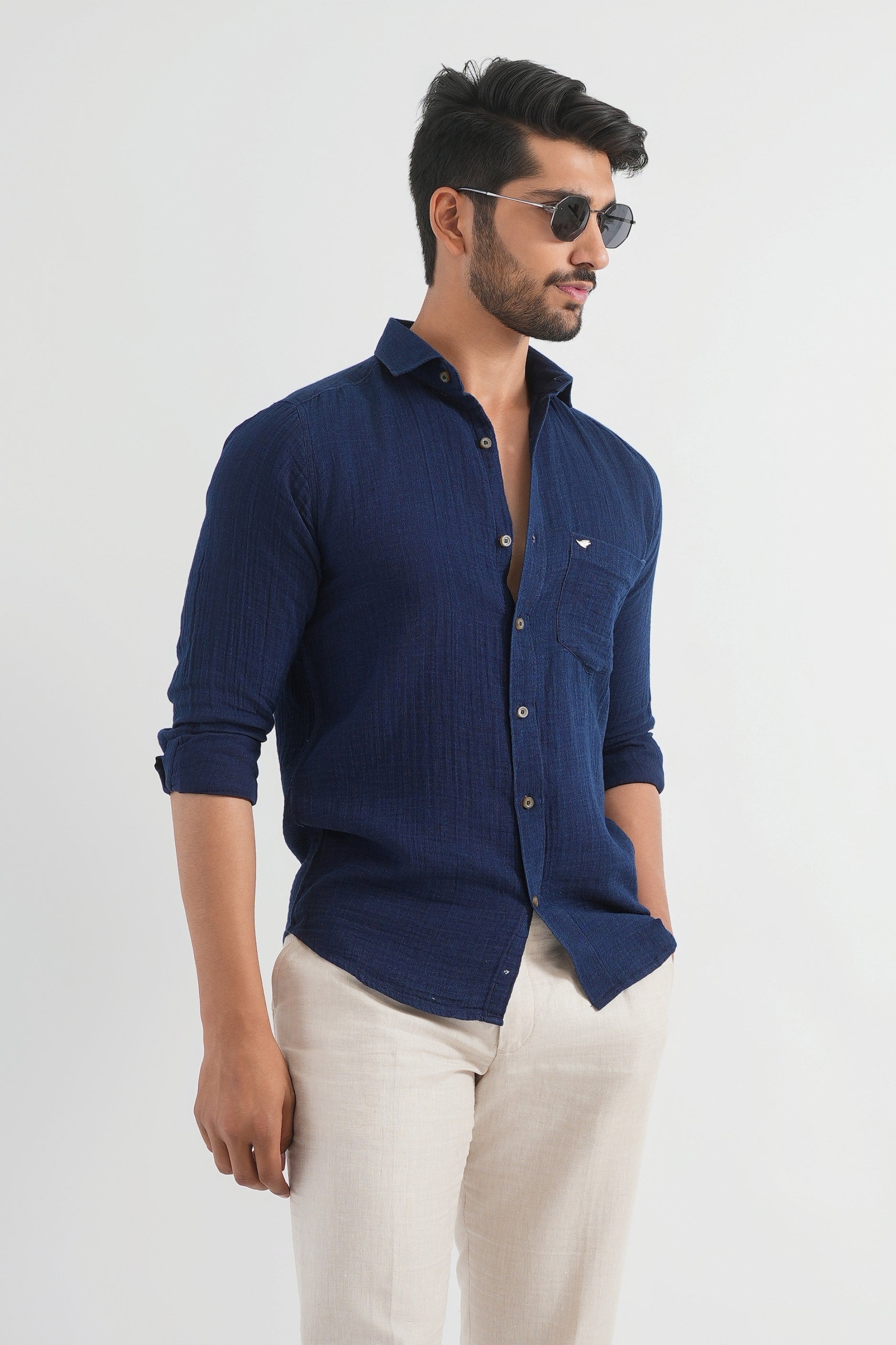 Man wearing a navy blue shirt and beige pants on a white background