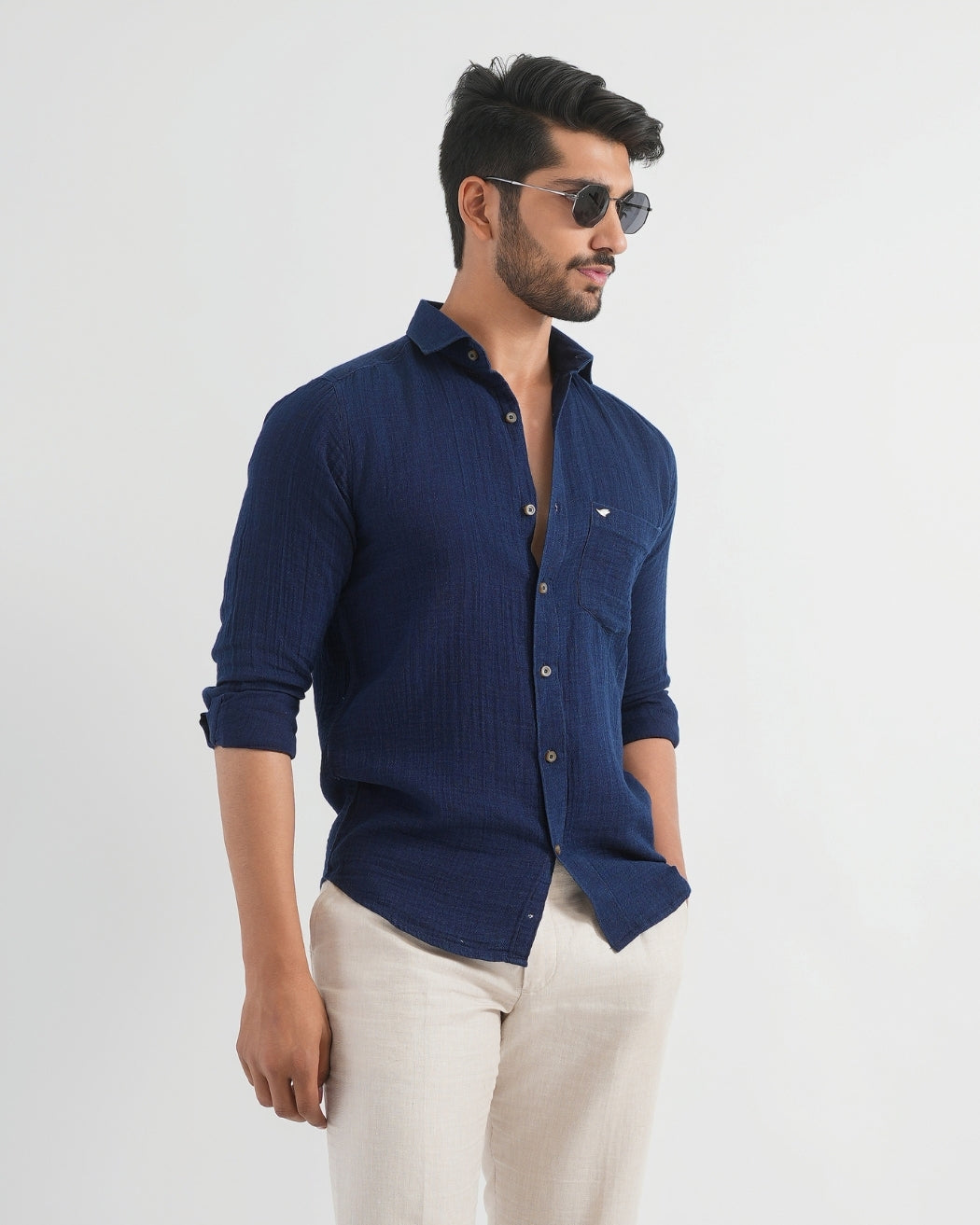 Man wearing a blue shirt and sunglasses on a white background