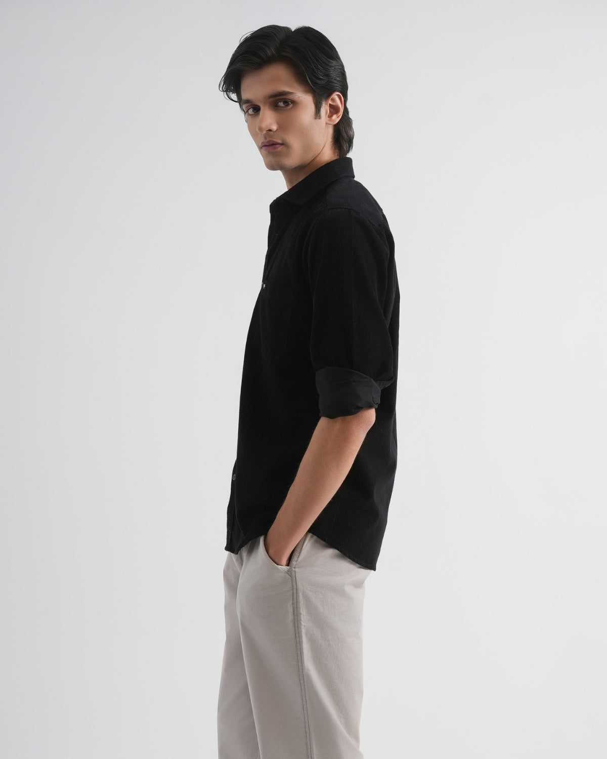 Man wearing a black shirt and light gray pants on a white background