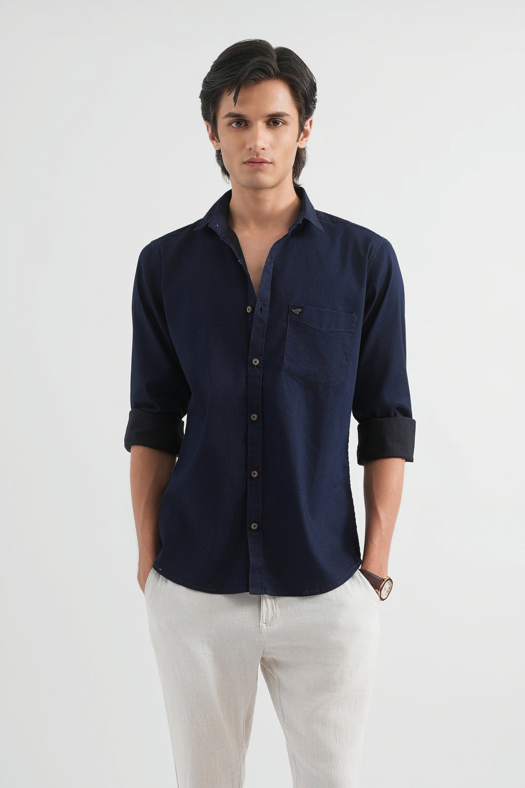 Man wearing a navy blue shirt and white pants on a white background