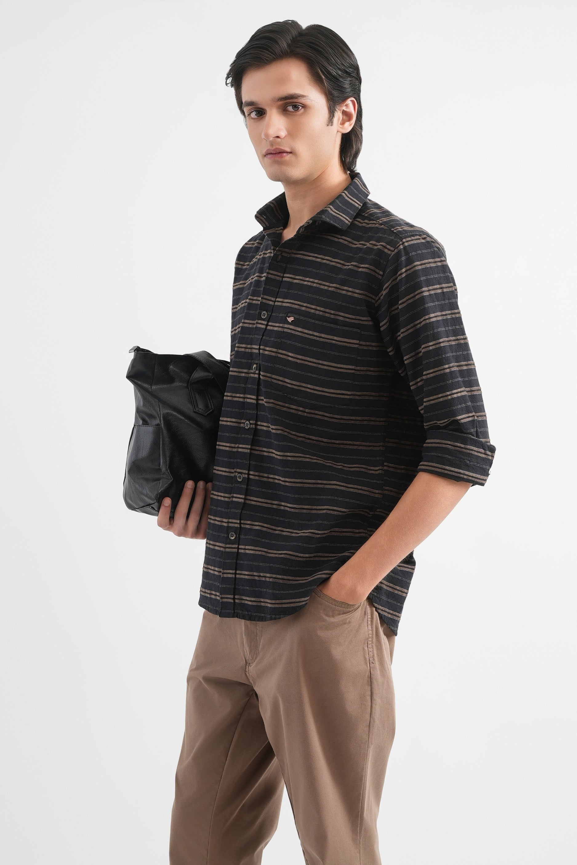 Man wearing a striped shirt and holding a black bag on a white background