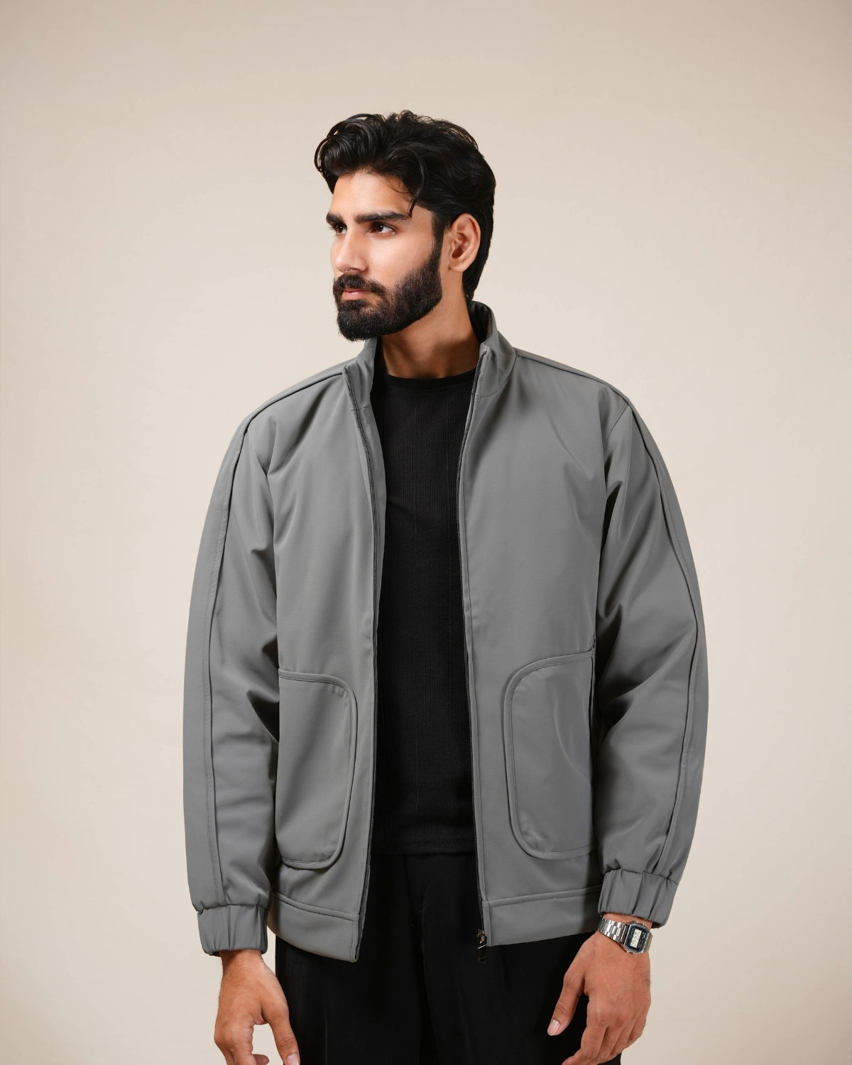 Man wearing a gray jacket over a black shirt on a beige background