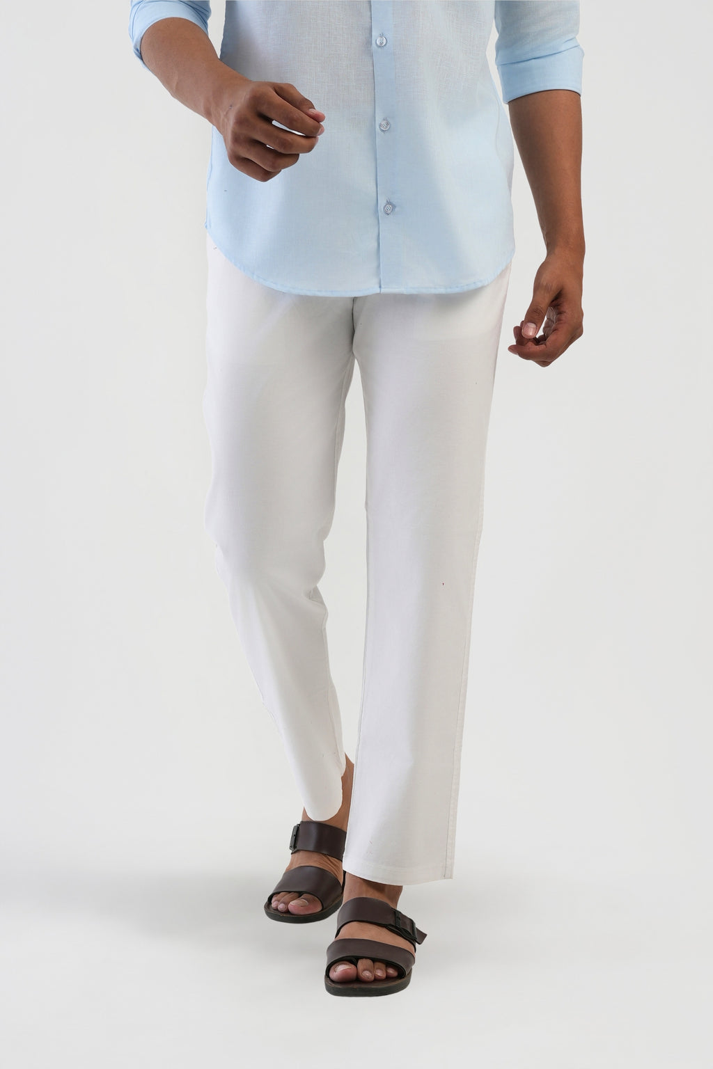 Person wearing a light blue shirt, white pants, and brown sandals on a white background