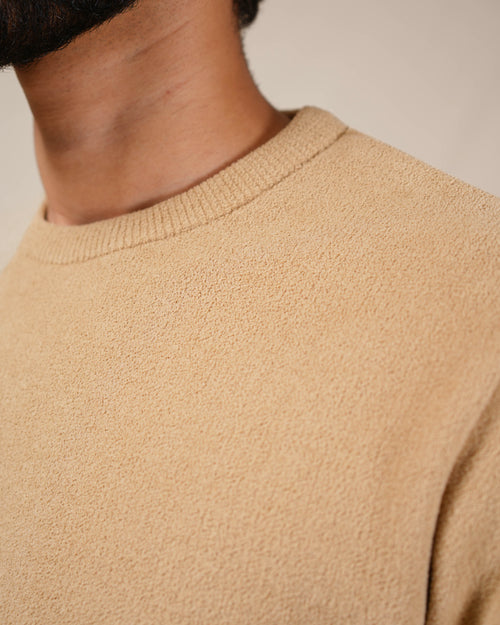 Close-up of a beige sweater with a neutral background