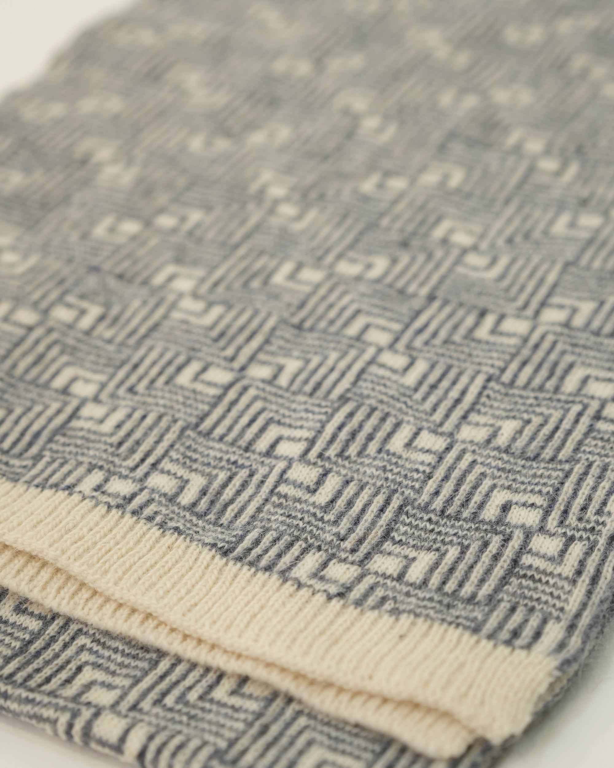 Close-up of a textured fabric with geometric pattern, featuring shades of blue and beige.