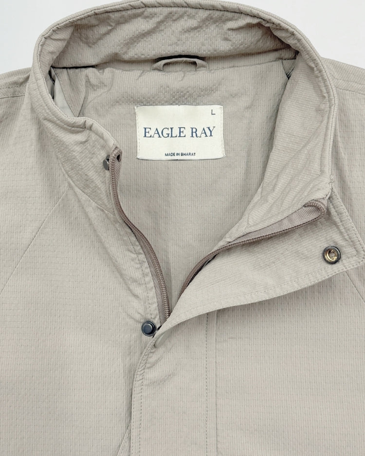 Close-up of a beige jacket with an Eagle Ray label on a light gray background
