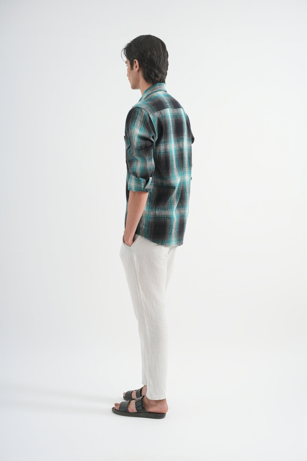 Person wearing a plaid shirt and white pants on a white background