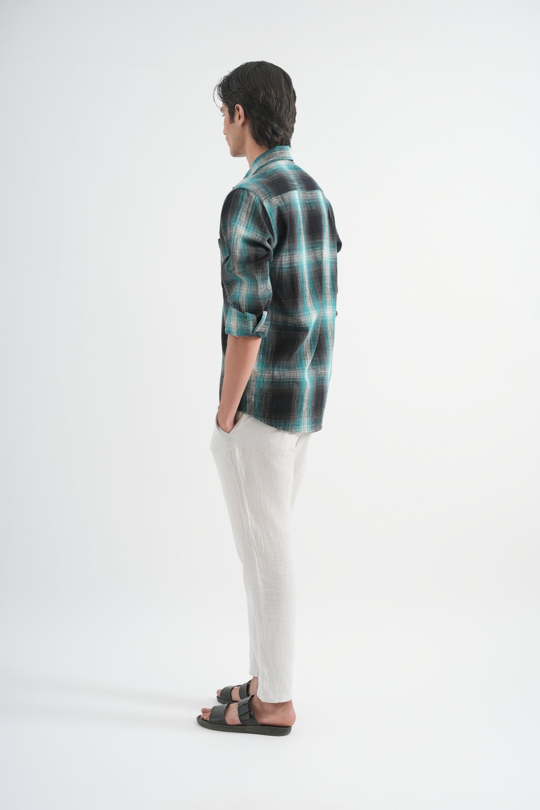 Person wearing a plaid shirt and white pants on a white background