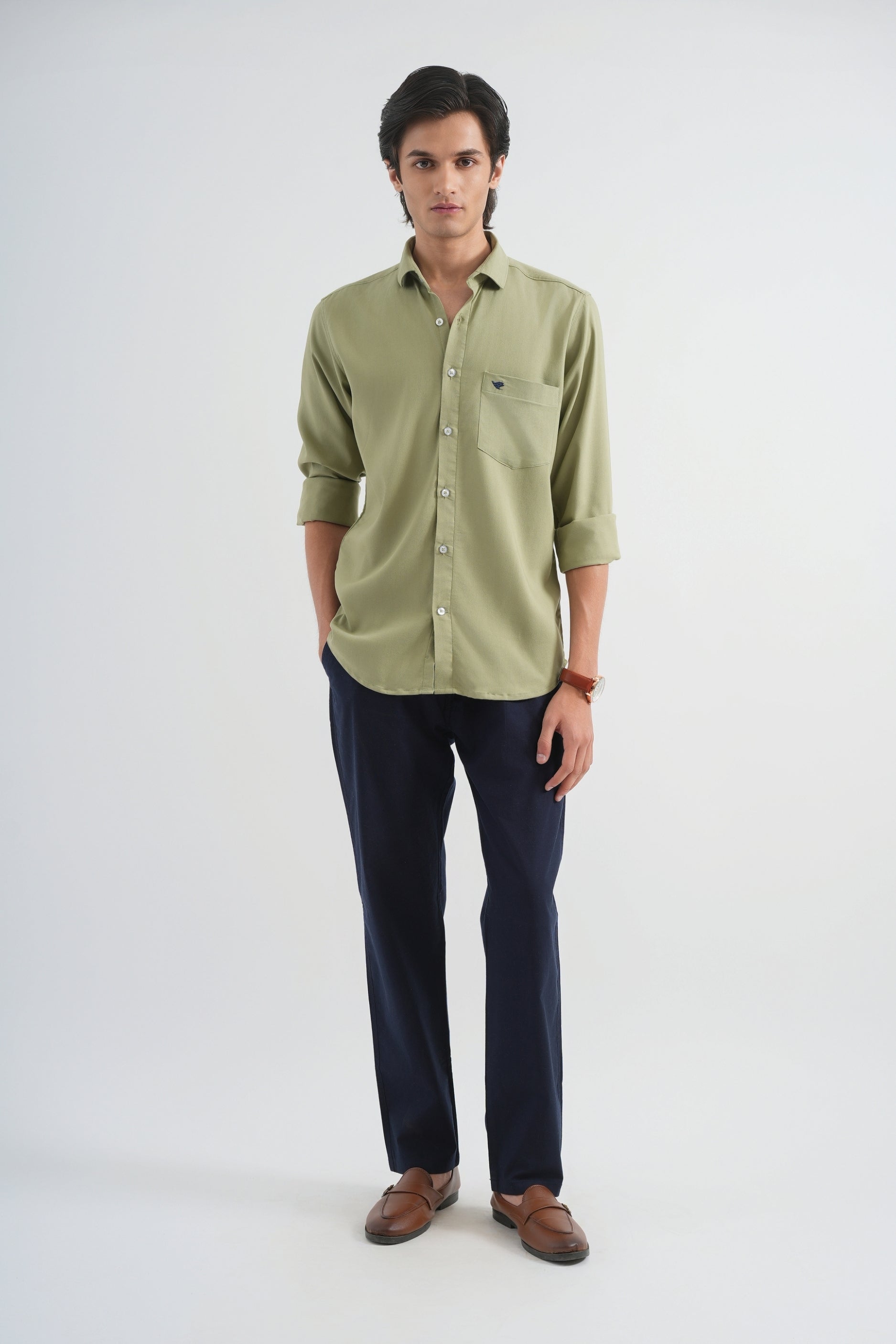 Man wearing a green shirt and dark pants on a white background