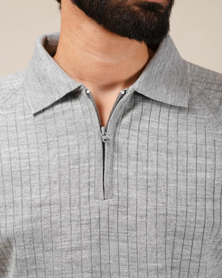 Close-up of a person wearing a gray ribbed sweater with a zipper.