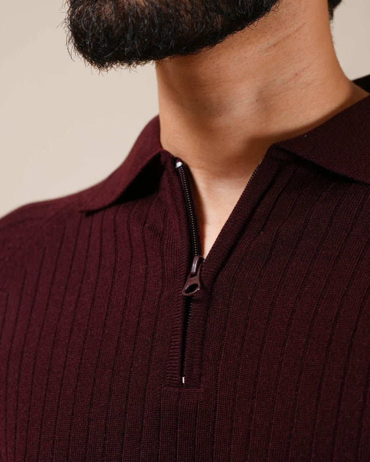 Close-up of a person wearing a ribbed brown sweater with a zipper.