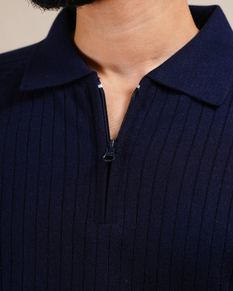Navy ribbed sweater with a zipper detail on a neutral background
