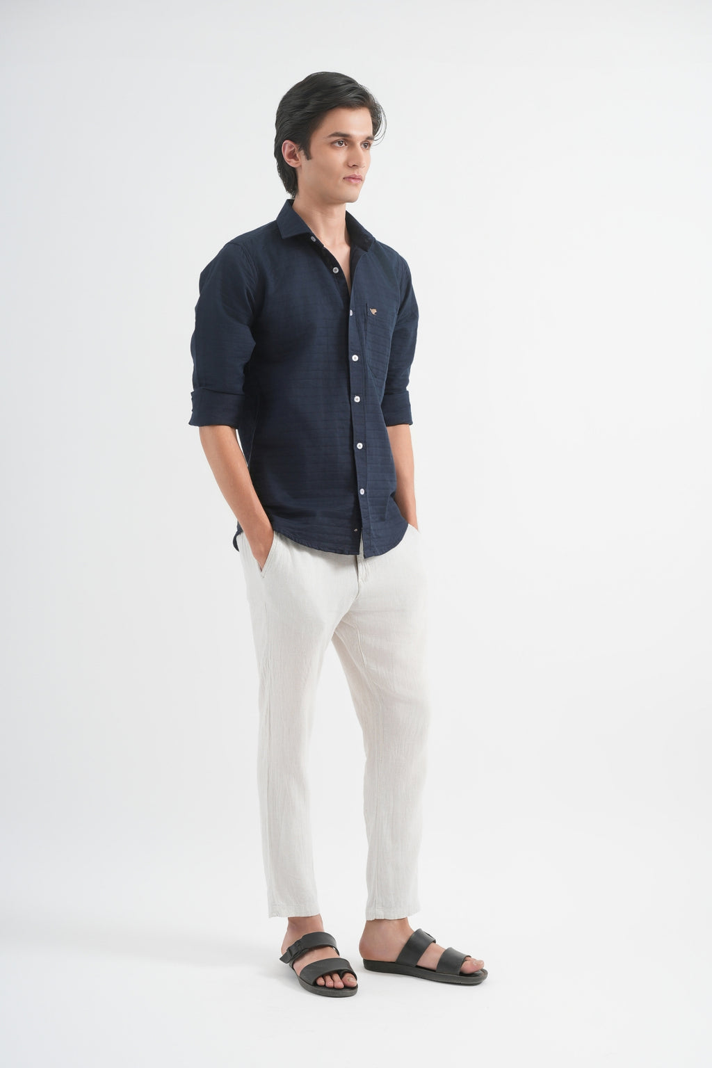 Man wearing a dark shirt and light pants on a white background
