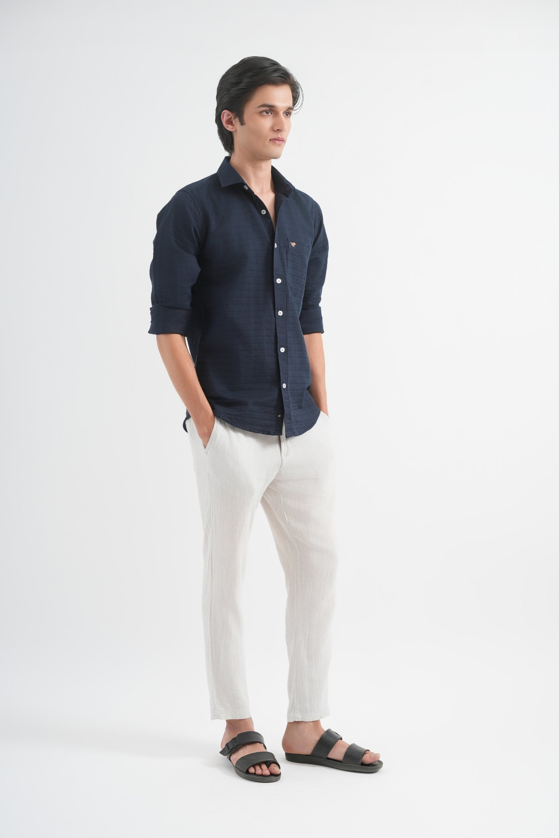 Man wearing a dark shirt and light pants on a white background