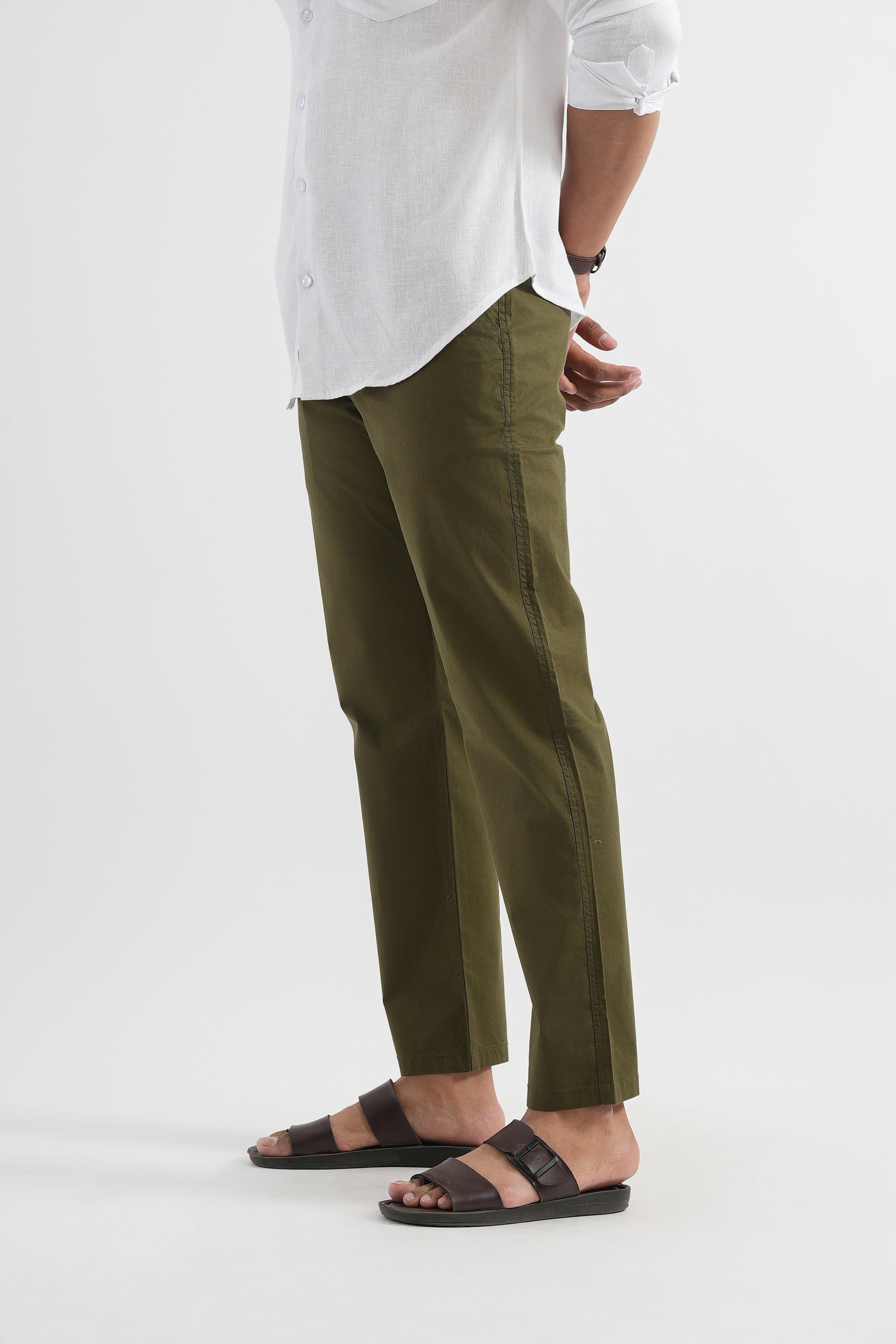 Person wearing green pants and white shirt on a plain background