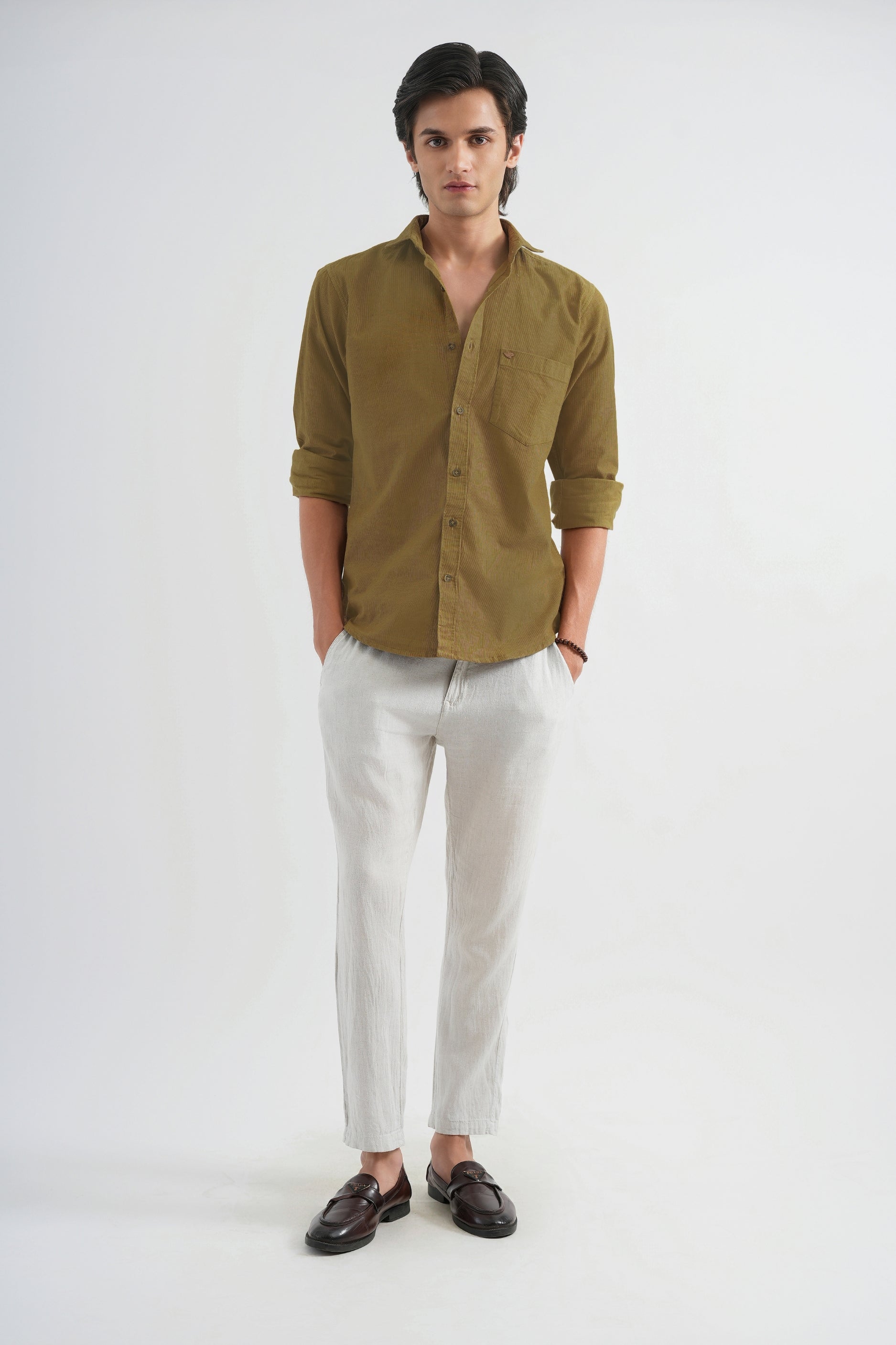 Man wearing a green shirt and light-colored pants on a white background