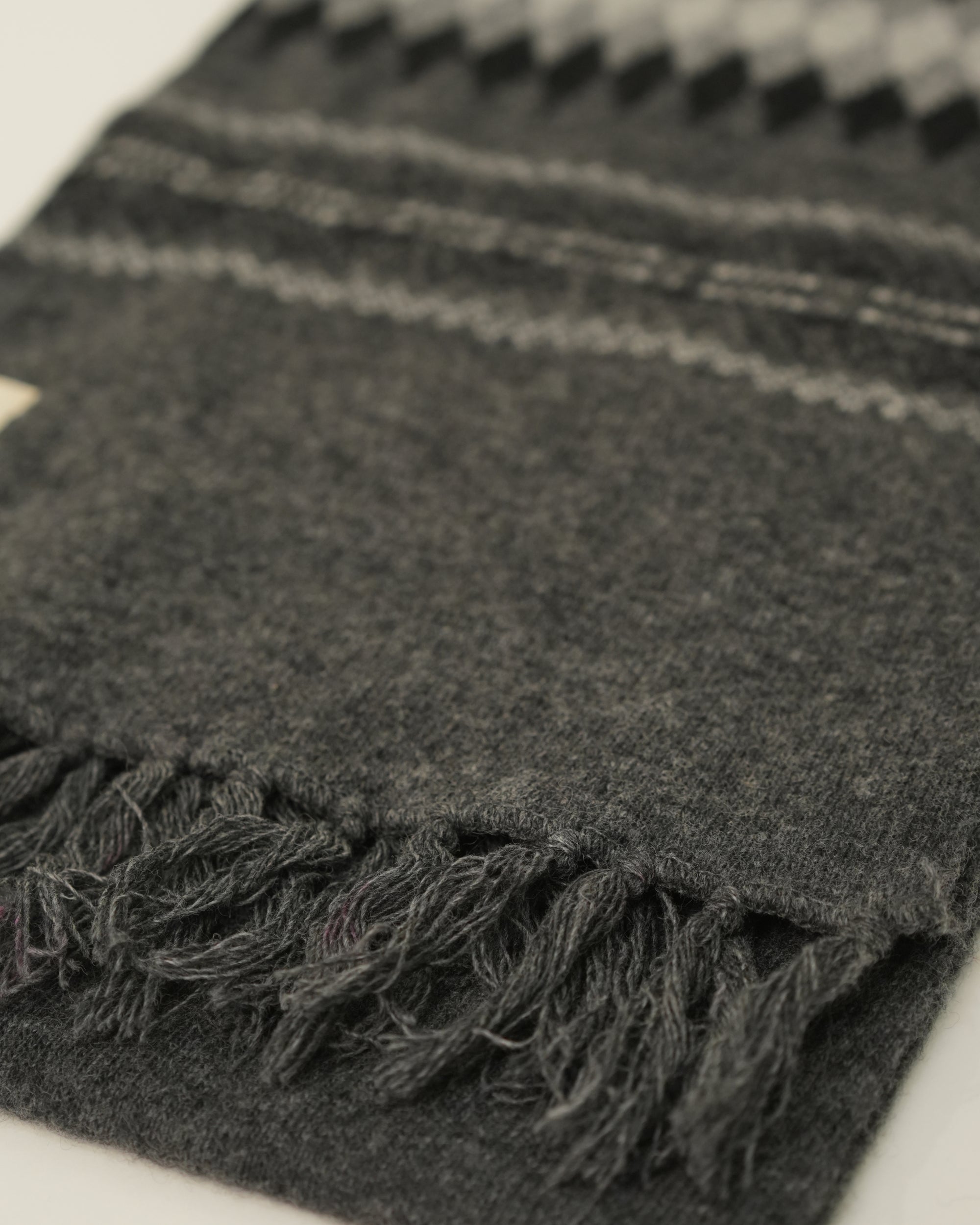 Close-up of a dark gray blanket with frayed edges on a light background