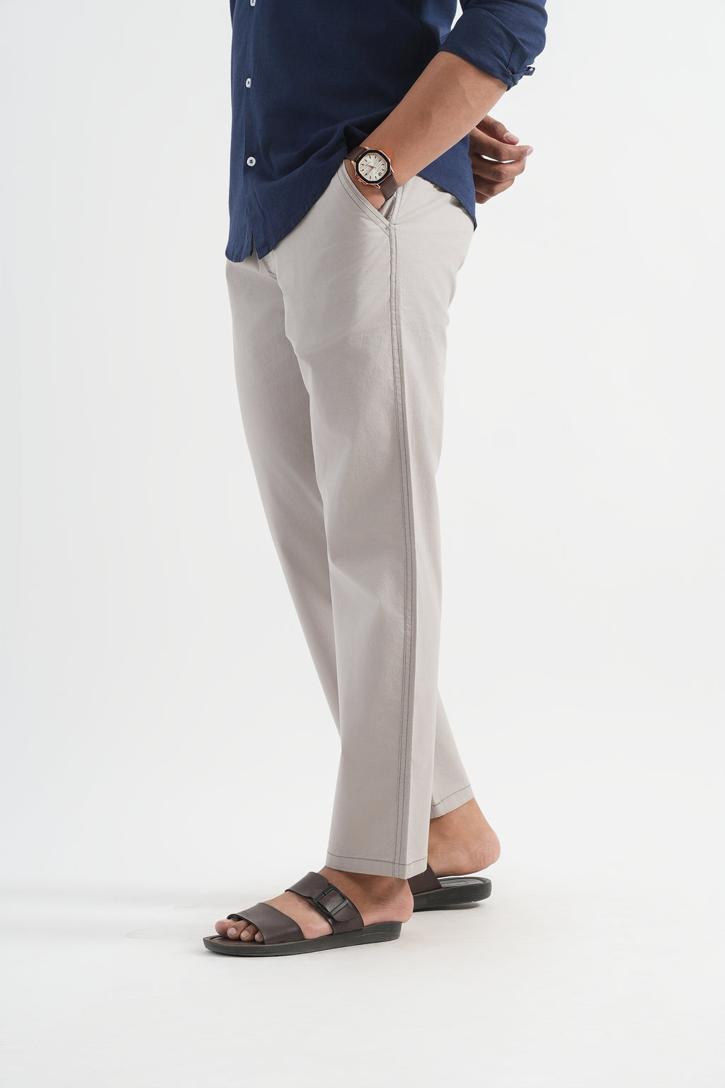 Person wearing a blue shirt, gray pants, and black sandals on a white background