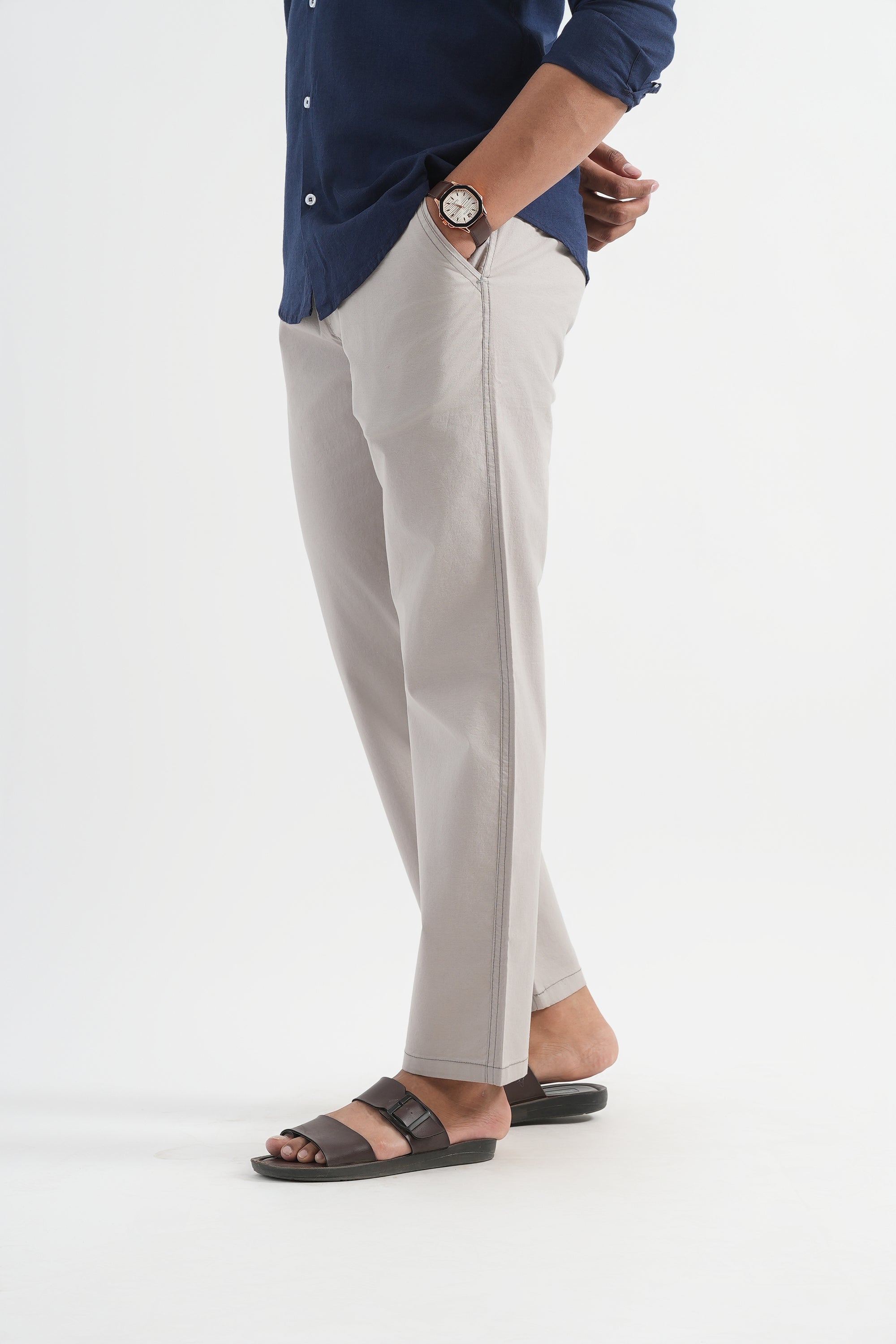 Person wearing a blue shirt, gray pants, and black sandals on a white background