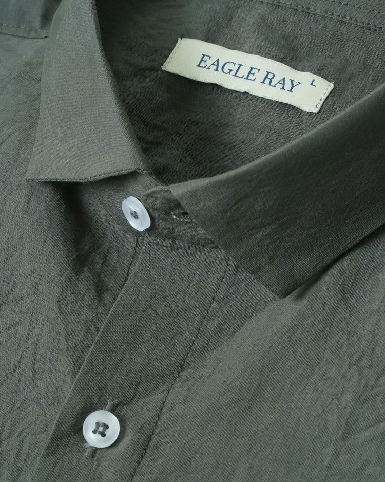 Close-up of a green shirt with a visible brand label on a plain background