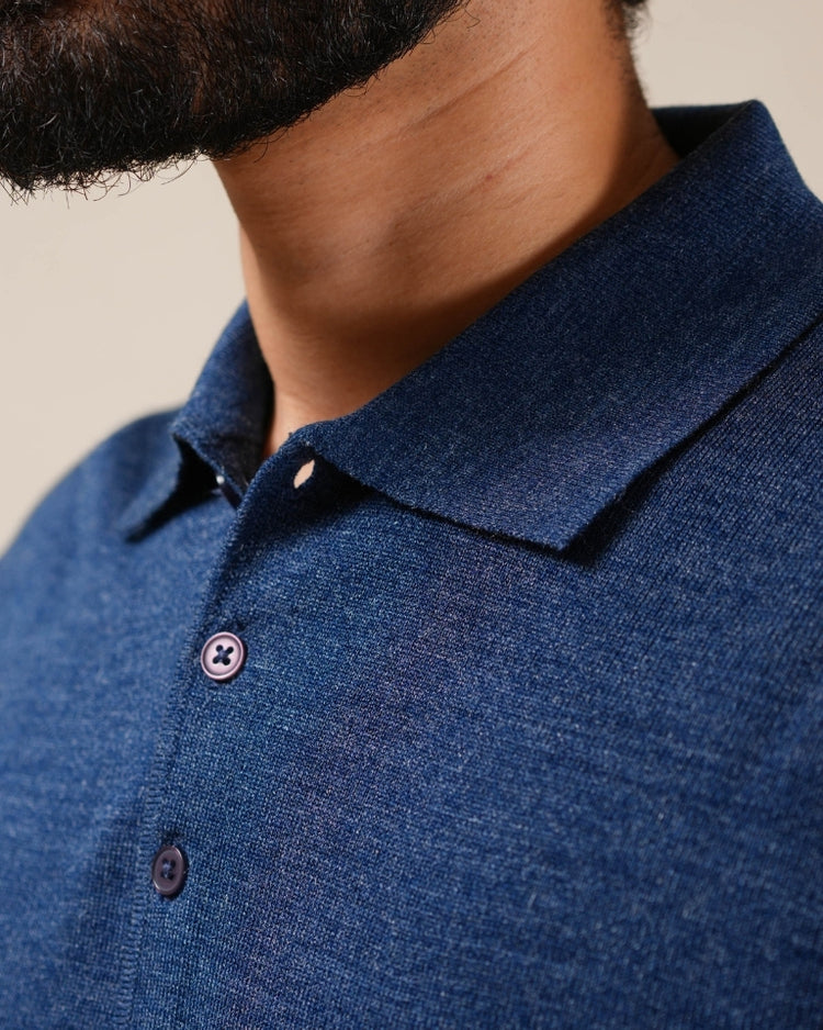 Close-up of a person wearing a blue polo shirt with a neutral background