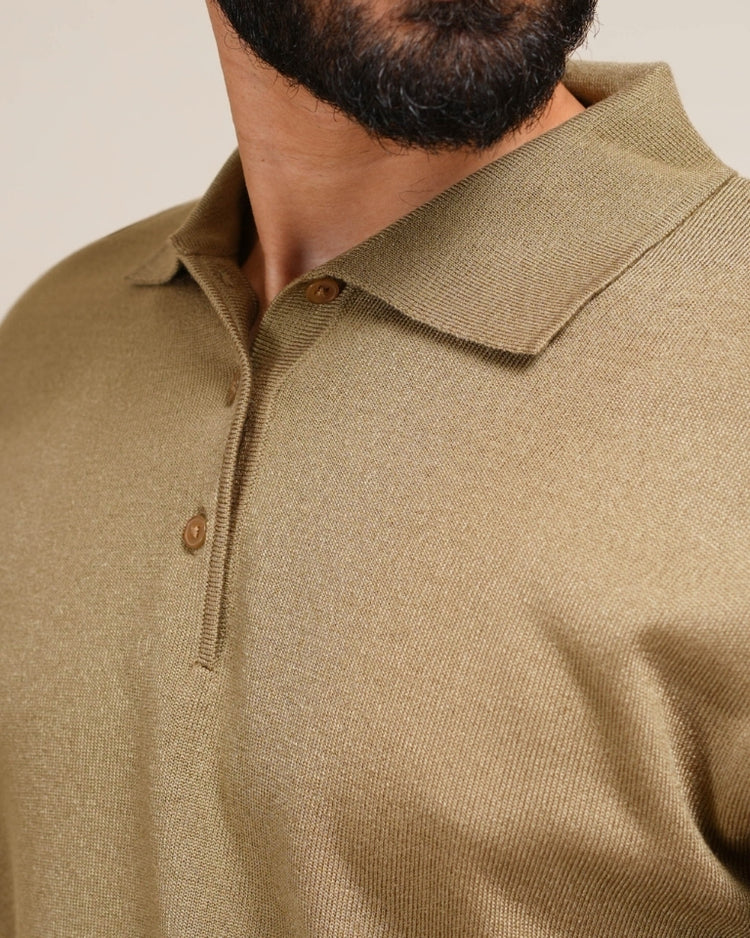 Close-up of a person wearing a brown knitted polo shirt with a neutral background