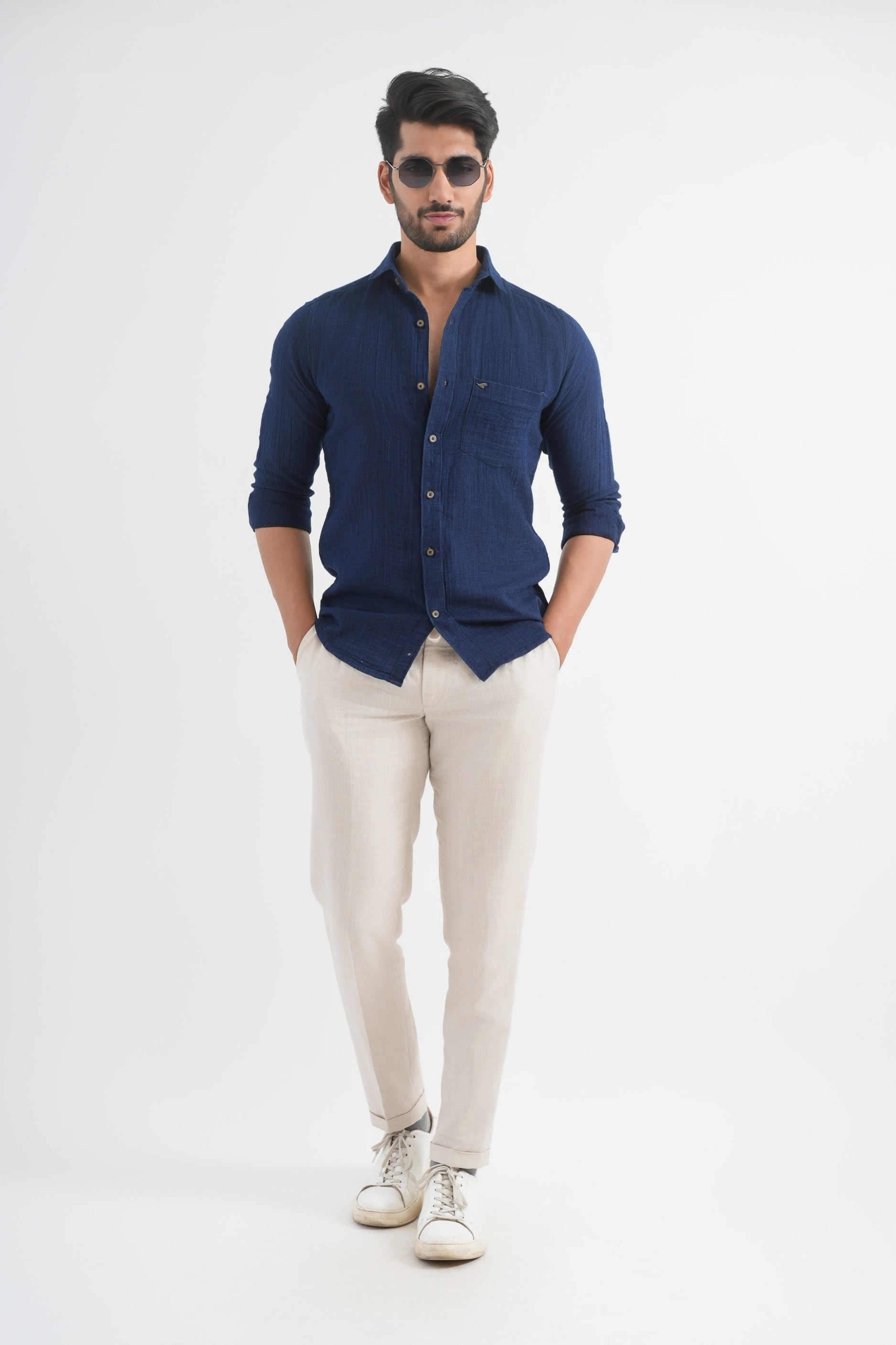 Man wearing a navy shirt and beige pants on a white background