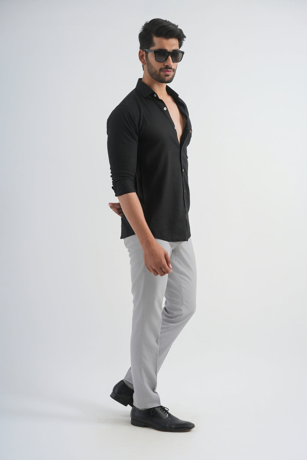 Man wearing a black shirt and gray pants on a white background
