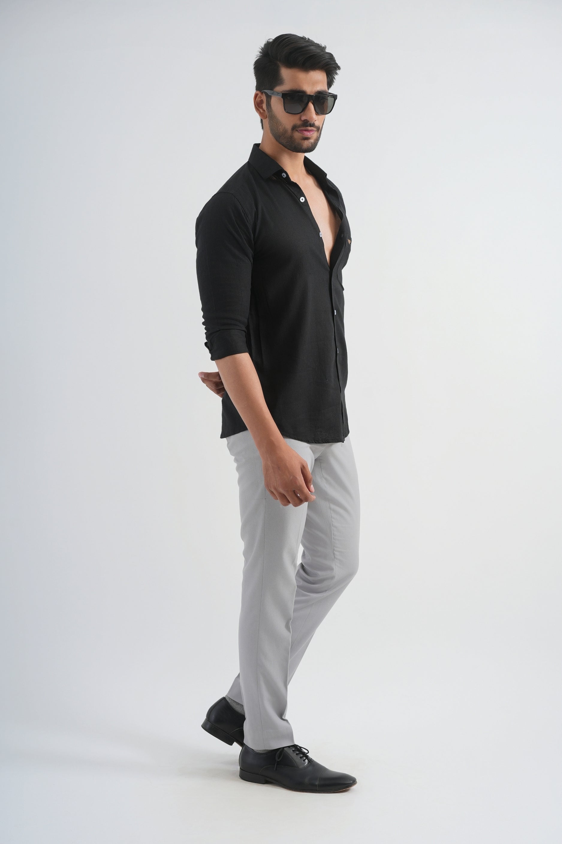 Man wearing a black shirt and gray pants on a white background