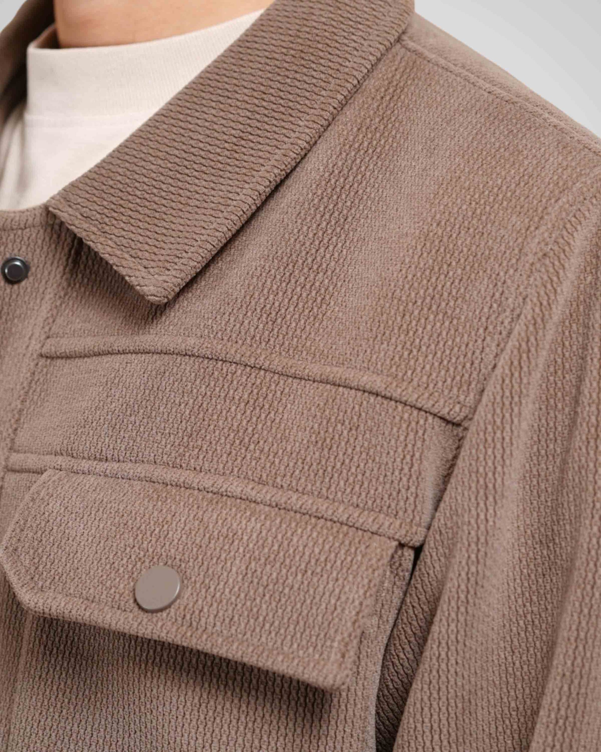 Close-up of a brown textured jacket with a collar and button details.