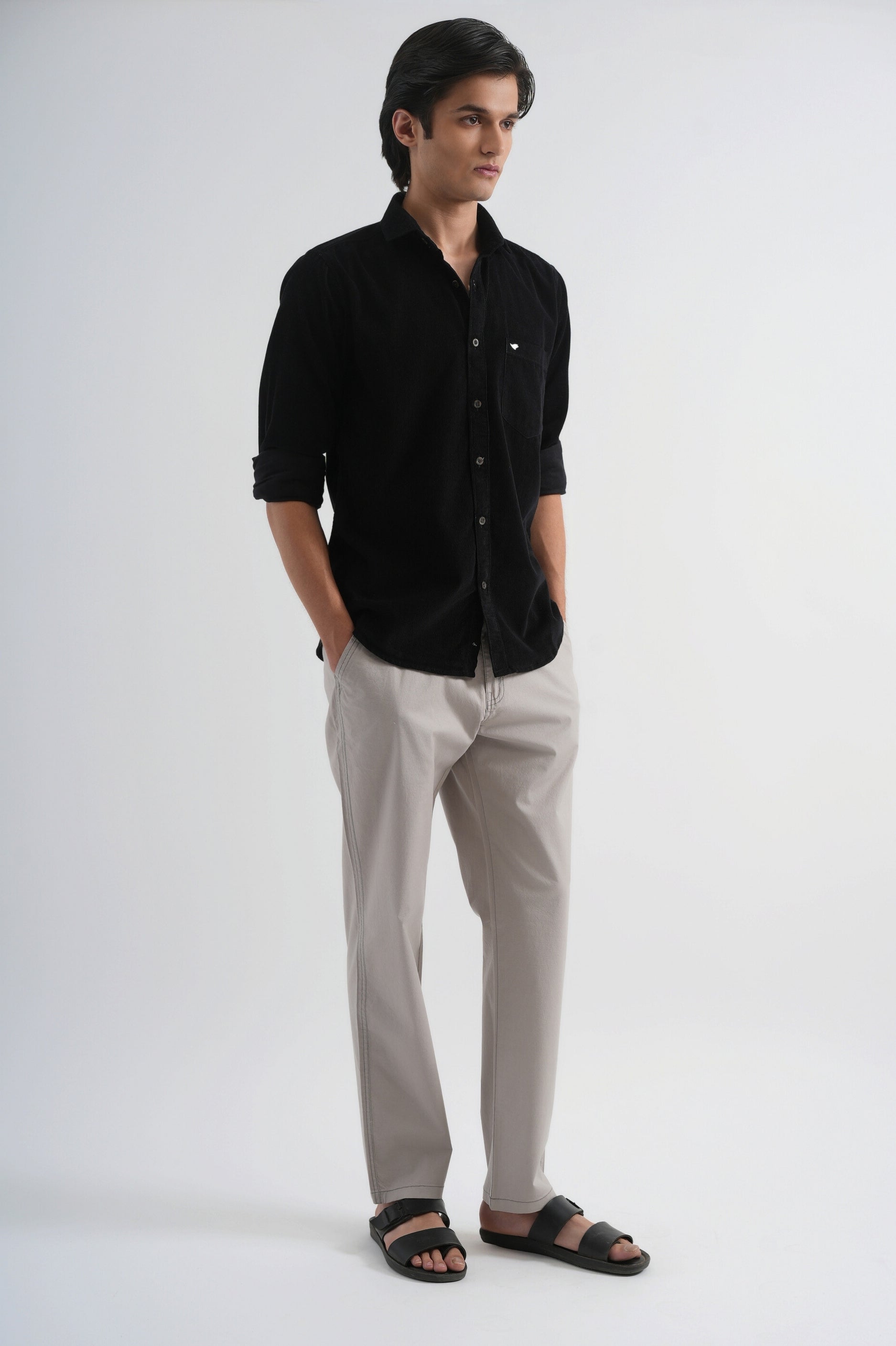 Man wearing a black shirt and gray pants on a white background
