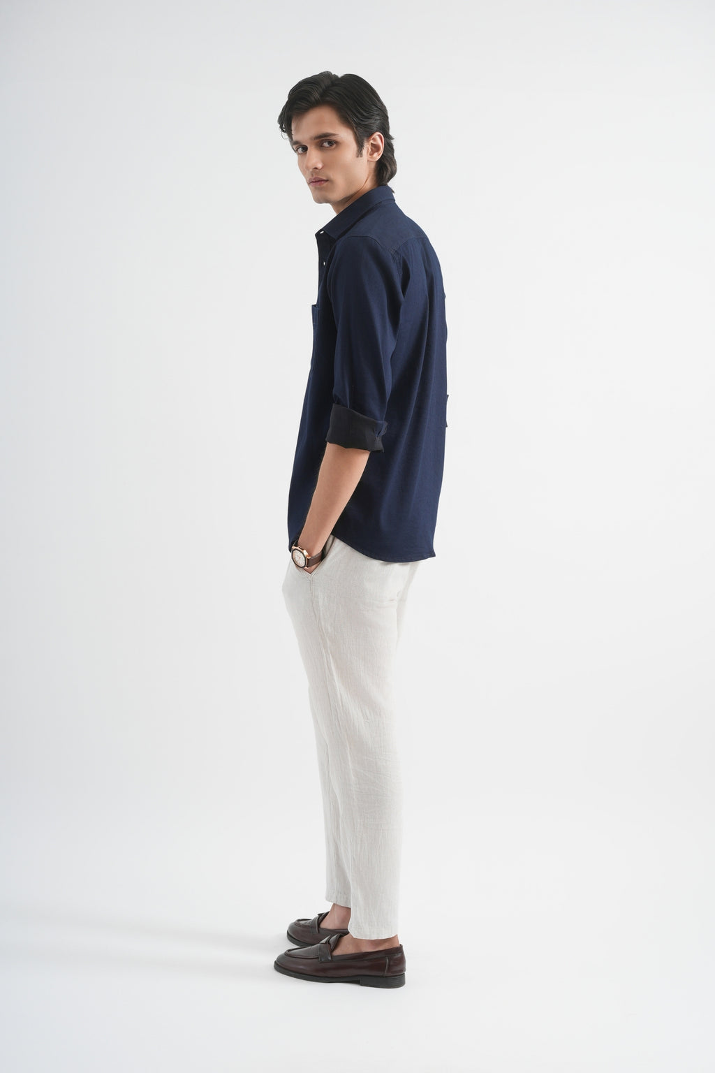 Man wearing a navy shirt and white pants on a white background