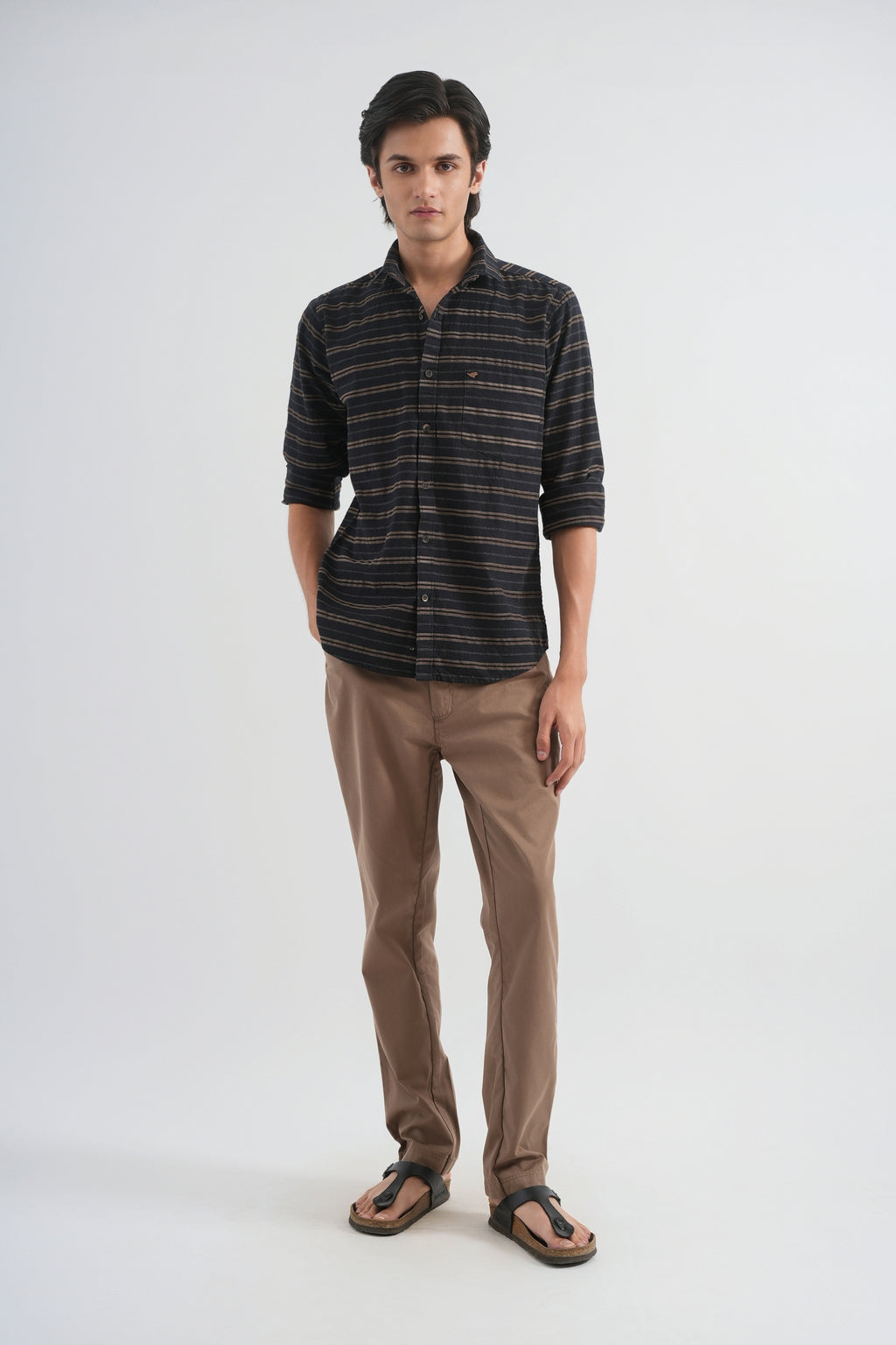 Man wearing a striped shirt and brown pants on a white background