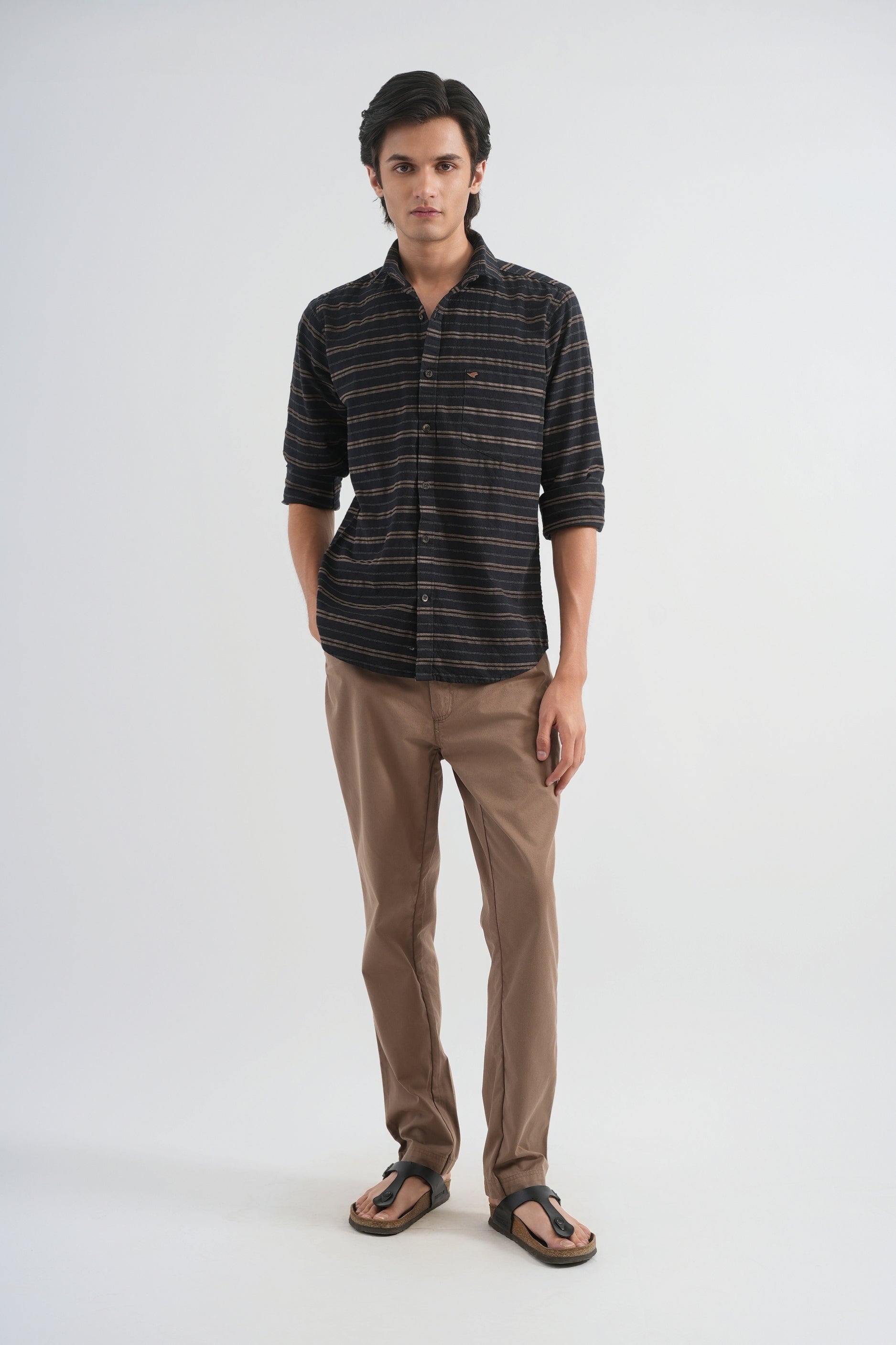 Man wearing a striped shirt and brown pants on a white background