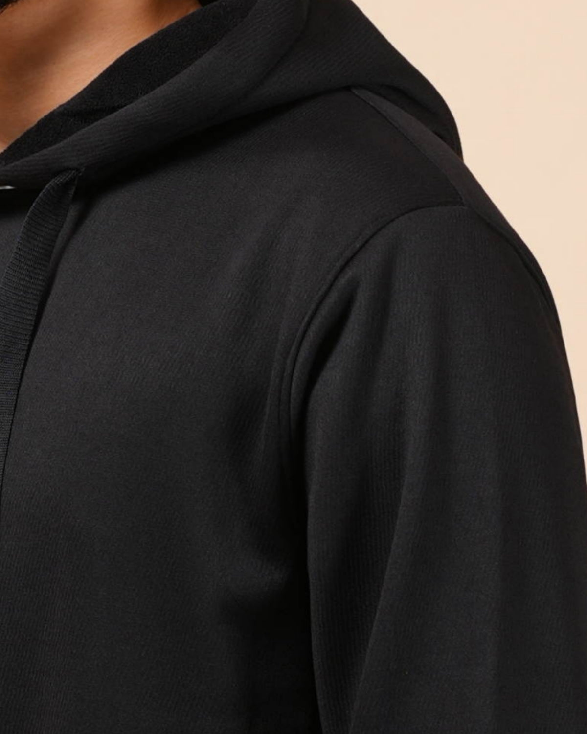 Close-up of a black hoodie on a beige background